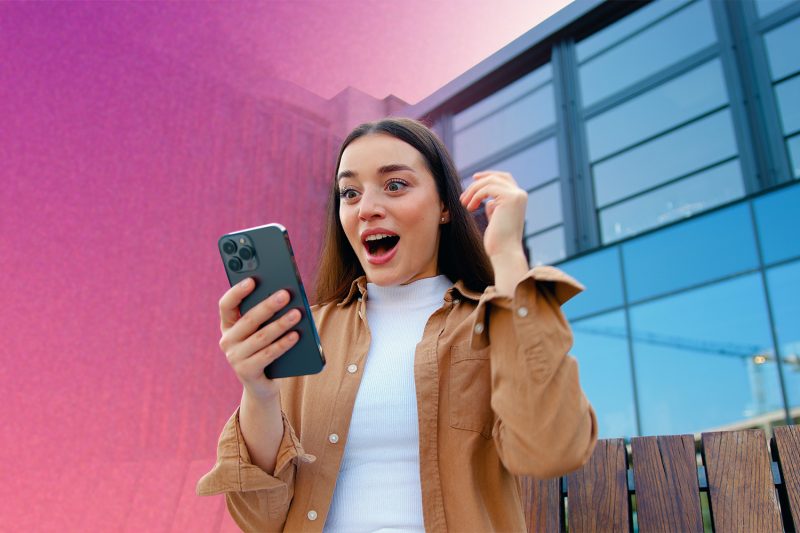 kobieta patrząca na telefon, uśmiechnięta szczęśliwa