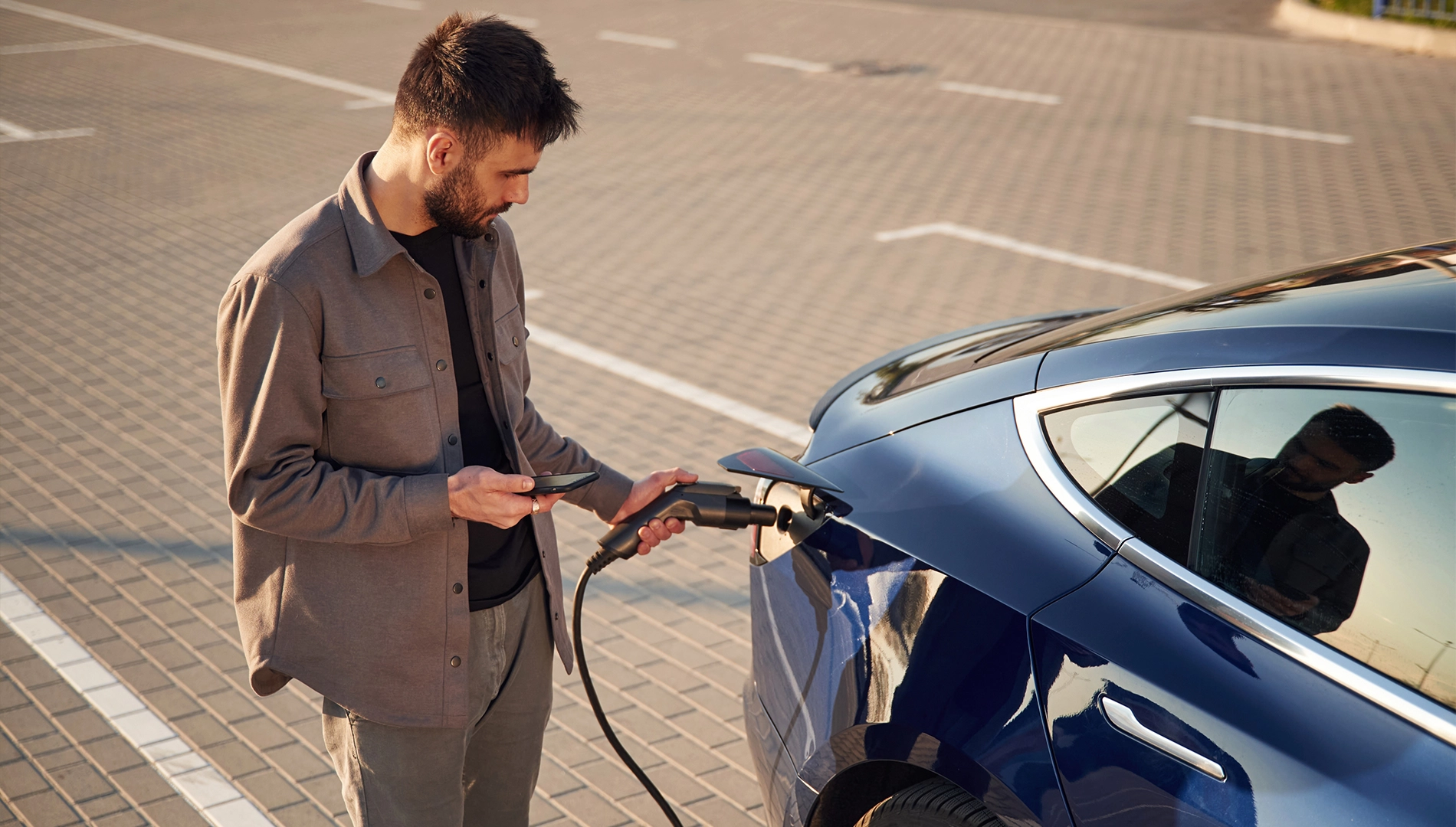 mężczyzna ładujący samochód elektryczny